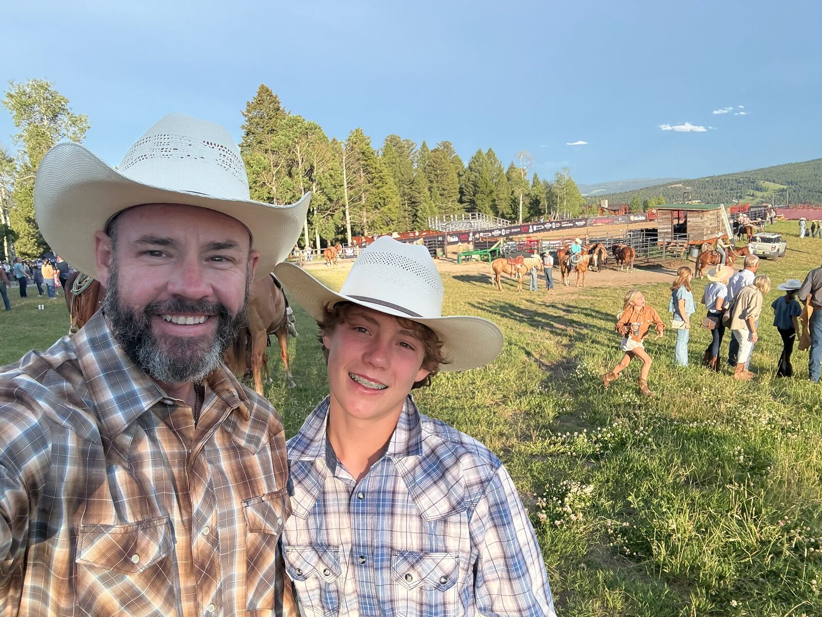 Mark and Dylan at the rodeo grounds with horses behind